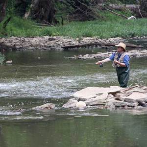 man fishing in blue river